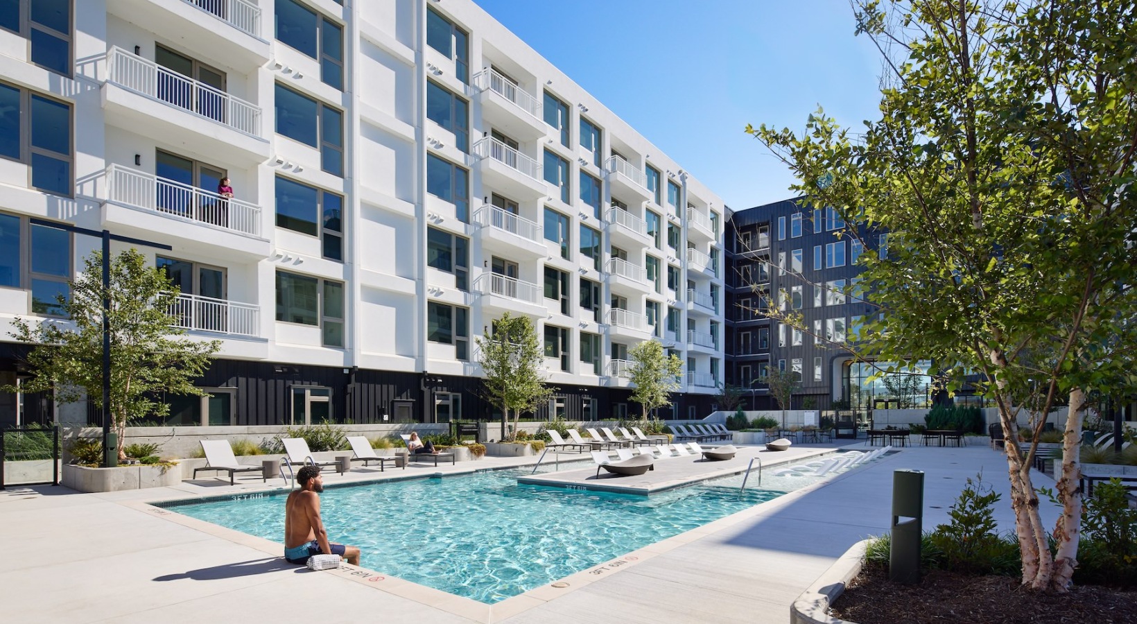 resort style pool with seating in a courtyard with some sitting near it