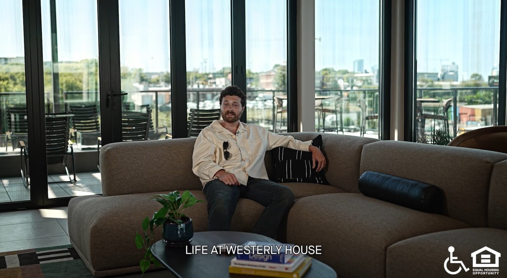 a person sitting on a couch with large windows behind them
